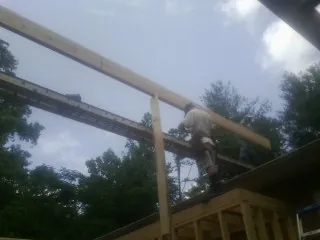 Carpenter setting a ridge beam over a new addition frame — Ice Dam Removal by Roofing Brothers in Cuero