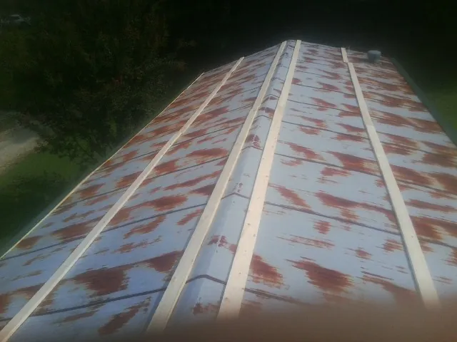 Rusted metal roof panels with new wood purlins before replacement — Storm Damage Roof Repair in Cuero by Roofing Brothers