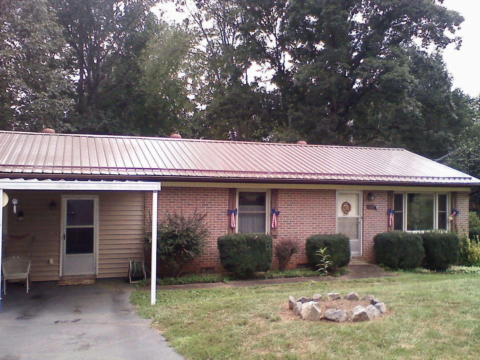Bronze metal roof and carport on a brick ranch home — Roof Repair work by our crew in Cuero